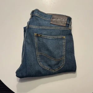 Blå Lee jeans med raka ben - Snygga blå jeans från Lee med klassisk femficksdesign och tydliga kontrastsömmar. Jeansen har rak passform och normal midja, tillverkade i slitstarkt denimtyg. Perfekta för en avslappnad och stilren look.