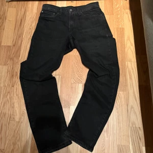 Svarta Levis 501 jeans straight fit W31 L32 - Svarta Levis 501 jeans med klassisk straight fit och fem fickor. Jeansen har knappgylf och den ikoniska Levis-lappen bak i midjan. Snygg, enkel design som funkar till allt. Materialet är robust denim i bomull.