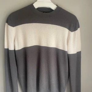 Randig tröja från Massimo Dutti - Snygg långärmad tröja från Massimo Dutti med breda horisontella ränder i grått och vitt. Tillverkad i en lyxig mix av ull, silke och kashmir som känns mjuk mot huden. Rund hals och klassisk passform, perfekt för dig som gillar stilrena vibes. Det är storlek M men passar även S