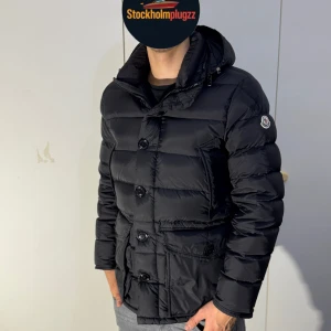 Svart Moncler dunjacka med huva - Svart dunjacka från Moncler med avtagbar huva och pälsdetalj. Jackan har stora knappar framtill, dragkedja och fyra rymliga  fickor där fram . Klassisk Moncler-logga på ärmen och fräsch design. Perfekt för kalla dagar ❄️och riktigt snygg passform. Storlek 2 som motsvarar M.  Pris går att diskuteras vid snabb affär ✅. Fraktar inom 24h 💨📦