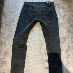 DONDUP jeans herr 31 - Säljer ett par svarta jeans från dondup  i slim fit med klassisk femficksdesign och smal passform. Jeansen har svarta sömmar och är tillverkade i ett stretchigt jeansmaterial som sitter tajt längs benen. Perfekt för dig som gillar en modern och stilren look. 