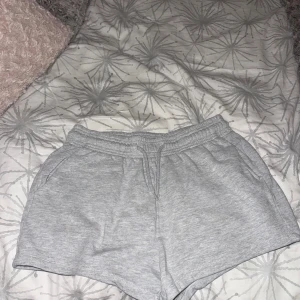 Grå mjuka shorts från 157, storlek S - Säljer ett par grå mjukisshorts från 157 i storlek S. De har elastisk midja med snörning och två sidofickor. Perfekta för chill dagar eller när du vill vara bekväm. Materialet är mjukt och känns skönt mot huden.