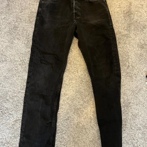 Svarta loose jeans från Jack and Jones 29/30 - Svarta jeans från Jack and Jones i loose fit-modell, storlek 29/30. Klassisk femficksdesign med raka ben och knappgylf. Snyggt slitna och tillverkade i robust jeanstyg som passar perfekt till sneakers eller boots.