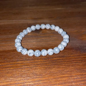 Vitt pärlarmband med marmormönster - Stilrent armband med runda vita pärlor och grått marmormönster. Elastiskt band gör det enkelt att ta på och av. Perfekt accessoar för dig som gillar minimalistisk och trendig stil.