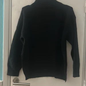 Svart polotröja med lång ärm - Svart polotröja med hög krage och långa ärmar. Tröjan är stickad och har en enkel, klassisk design som funkar till många olika stilar. Materialet känns mjukt och värmande, perfekt för kyliga dagar. Passformen är normal och modellen är tidlös. Endast testad