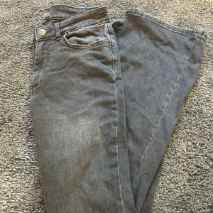 Mörkgrå bootcut jeans från ONLY - Snygga mörkgrå jeans från ONLY med klassisk femficksdesign och bootcut-ben. Jeansen har lågmidja och är tillverkade i mjukt denim-material som sitter skönt. Perfekt för dig som gillar en avslappnad men stilren look.