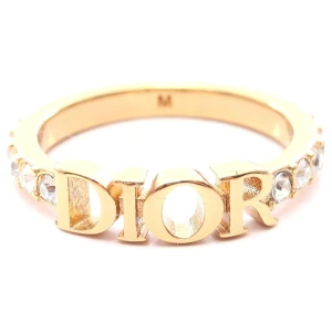 Guldig Dio(r) evolution ring - Superfin ring från Dior i guldton med stora bokstäver som stavar DIOR framtill. Ringen är dekorerad med gnistrande stenar runt hela bandet för extra bling. Perfekt statement piece för dig som gillar lyxiga accessoarer och vill sticka ut. Storlek M som är 16,5mm.