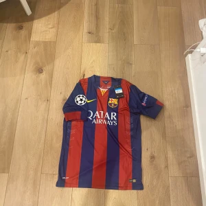 FC Barcelona Messi 10 matchtröja Nike M - Säljer en officiell FC Barcelona fotbollströja med Messi 10 på ryggen. Tröjan är randig i mörkblått och rött, med gula detaljer och Champions League-märke på ärmen. Tillverkad i ventilerande Dri-FIT material för maximal komfort. Qatar Airways och UNICEF-logga finns tryckt.