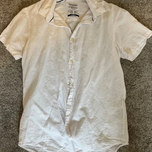 Vit kortärmad skjorta Essentials M - Fräsch vit skjorta från Essentials by Jack & Jones i storlek M. Skjortan har klassisk krage, korta ärmar och knappar framtill. Tillverkad i en skön blandning av bomull och linne, perfekt för varma dagar. Enkel och stilren design som funkar till många olika looks.