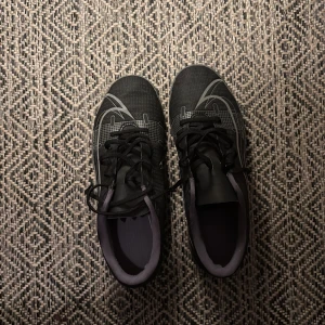 Svarta Nike sneakers med grå detaljer - Säljer ett par svarta Nike sneakers med grå detaljer och snörning. Skorna säljs för de är för små för mig.