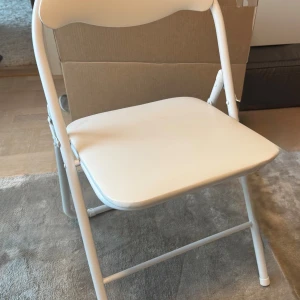 Vit stol - En vit, hopfällbar stol i metall. Produkten är i gott skick med minimalt slitage. Hämtas upp i Stockholm skickas ej