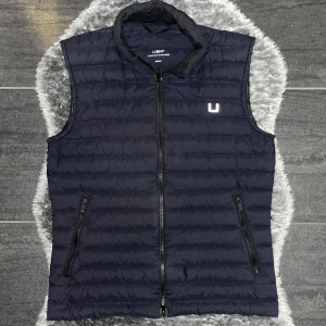 UBR Super Sonic Vest Navy - UBR Super Sonic väst i marinblått (navy). Teknisk, lätt och stilren väst med hög kvalitet och modern passform. Storlek M. Mycket fint skick.