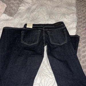 Ultra low flare jeans från Gina Tricot - Mörkblå jeans med kontrastsömmar från Gina Tricot, modell ultra low flare med låg midja och utsvängda ben. Klassisk femficksdesign och snygg passform som ger en cool retrovibe. Perfekt för dig som gillar statement-jeans med flare. 