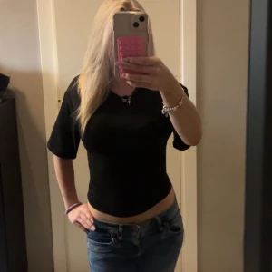 Svart croppad topp med kort ärm - Säljer en svart croppad topp med korta ärmar och rund hals. Toppen har en tight passform och är tillverkad i mjukt bomullsmaterial. Enkel och stilren design som är lätt att matcha med jeans eller kjol.