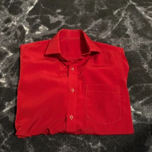 Röd manchesterskjorta med ficka - Riktigt snygg röd skjorta i manchester med klassisk krage, bröstficka och knäppning framtill. Skjortan har långa ärmar med manschett och en rak passform som ger en chill vibe. Perfekt för dig som vill sticka ut med färg och stil.