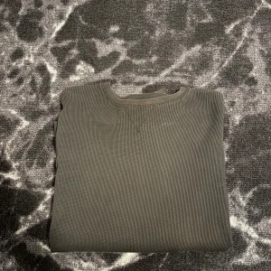 Svart långärmad tröja från Lindex - En svart långärmad tröja från Lindex i ribbad bomull. Tröjan har rund halsringning, diskret V-detalj vid halsen och muddar vid ärmsluten. Perfekt för lager-på-lager och chill vardagsstil.