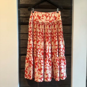 Härlig rödvit blommig långkjol Polo Ralph Lauren - Supersnygg långkjol från Polo Ralph Lauren med rödvitt blommönster. Kjolen har plisserade partier, volang nertill och dragkedja i sidan. Använd endast två gånger - nyskick! Som en svensk Small/Medium i strlk.  Nypris 3000 sek. 