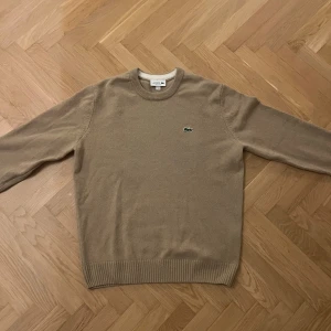 Beige stickad tröja från Lacoste - Sjukt snygg stickad tröja från Lacoste, använd 1-2 gånger pga för liten 