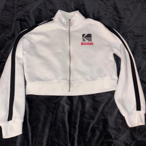 Vit croppad jacka trackjacket Kodak XS - Vit croppad jacka från Kodak med dragkedja och hög krage. Mjuk bomullskänsla och långärmad modell, perfekt för en chill streetstyle.