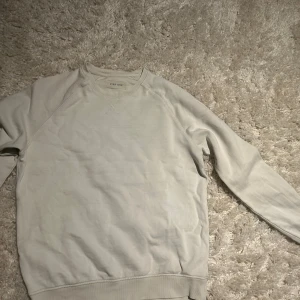 Ljusgrå sweatshirt från Pier One - En stilren ljusgrå sweatshirt från Pier One med klassisk rund halsringning och ribbade muddar. Tröjan är enkel och passar perfekt till jeans eller joggers. Tillverkad i mjuk bomull för en skön känsla hela dagen.