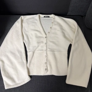 Slutsålda tröjan från Gina Tricot - Säljer en krämvit tröja från Gina Tricot med v-ringning och snygga pärlemorknappar. Koftan har ribbad nederdel och långa ärmar, perfekt för lager-på-lager. Mjuk och skön, passar till allt.