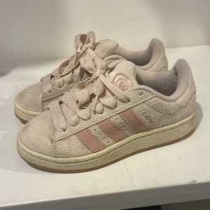 Adidas Campus  rosa  i mocka, strl 36 - Snygga Adidas sneakers i ljusrosa mocka med klassiska tre ränder i en mörkare rosa ton på sidan. Modellen har rund tå, platt sula och breda snören. Perfekt för dig som gillar en soft och clean look med lite retrovibe.