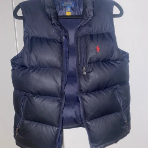 Polo Ralph lauren väst - En skön blå Polo Ralph Lauren väst, passar perfekt under alla säsonger. Säljes i befintligt skick, ett litet hål på baksidan som går att åtgärda. Hör av dig för mer info!