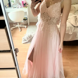 ljusrosa balklänning - Superfin ljusrosa långklänning med tunna axelband, v-ringning och blommiga spetsdetaljer. Kjolen är i flera lager tunn tyll och har en slits framtill. Perfekt för bal eller student! Lappen finns kvar, skriv om det är något mr ni undrar🥰Jag är 170cm, nypriset var runt 1800+ den dyra frakten på jj house!☺️Kan tänka mig att ändra priset om ni kommer med bra bud!💕
