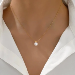Guldhalsband med vit pärla - Elegant halsband med tunn guldfärgad kedja och en rund vit pärla som hängsmycke. Perfekt för dig som gillar stilrena och klassiska smycken med en modern touch. Passar till skjorta eller enkel topp för en snygg look.