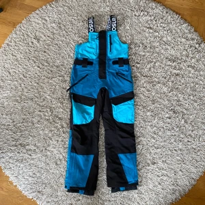 Skidbyxor Bib Tenson MPC Extreme - Tenson Bib TeSphere MPC Extreme Bib Pants. Kommer i en avslappnad passform och utrustade med Tenson’s MPC Extreme-teknologi (WP 10.000mm / MP 10.000 g/m2/24h) som kombinerar extremt effektiv vattentäthet med exceptionell andningsförmåga för att hålla dig bekväm under snöiga, blåsiga och blöta förhållanden. Eftersom modellen sitter mycket högt och har snölås vid bensluten skyddar byxorna bra. Använda i skidbacken i 4 dagar men det märks knappt. Nypris 3200kr.⛷️