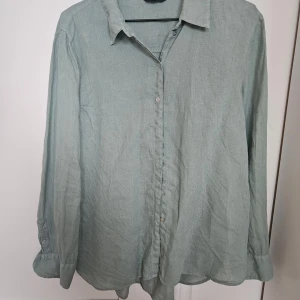 Ljusgrön linneskjorta Massimo Dutti - Snygg ljusgrön skjorta från Massimo Dutti i 100% linne. Klassisk krage, knäppning framtill och långa ärmar med manschett. Perfekt för en chill och stilren look.