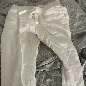 Vita linnebyxor med snörning - Snygga och luftiga vita linnebyxor med bekväm midja och snörning framtill. Perfekta för varma dagar och chill stil. Byxorna har en avslappnad passform och är tillverkade i svalt linnematerial.