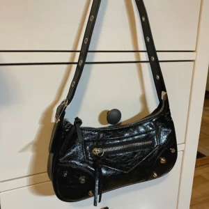 Svart axelväska med nitar - Cool svart axelväska med nitar, 3 olika fack. 