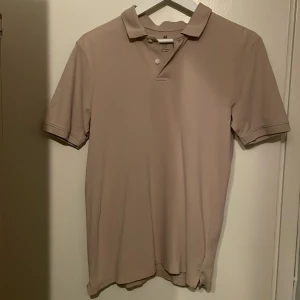 Beige pikétröja från H&M XS - Snygg beige pikétröja från H&M i storlek XS. Klassisk krage och två knappar framtill. Regular fit som sitter bra. 