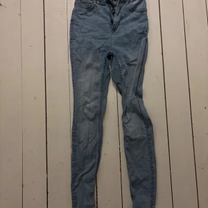 Ljusblå skinny jeans - Säljer ett par ljusblå jeans med skinny passform och klassisk femficksdesign. Jeansen har dragkedja och knapp framtill, samt smal siluett hela vägen ner. Perfekt för dig som gillar en tajt look och ljusa denimtoner.