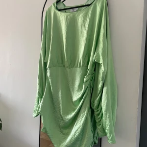 Långärmad grön klänning - Väldigt fin långärmad klänning från Hanna Schönbergs collection med NA-KD, storlek 40 i väldigt fint skick. Dragkedja längs ena sidan, vida ärmar & fina detaljer på ärmarna och sidorna. Säljer även en likadan i svart. 💕