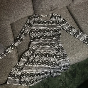 Svartvit mönstrad långärmad klänning - Svartvit klänning med grafiskt mönster och lång ärm. Klänningen har en v-ringad rygg. Materialet känns mjukt och stretchigt, troligen polyester. Perfekt för dig som gillar coola kontraster och unika prints.