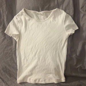 Vit basic t-shirt från BikBok - Enkel och stilren vit t-shirt från GinaTricot, modell Basically Basic. T-shirten har rund halsringning och korta ärmar. Tillverkad i mjuk bomull som känns skön mot huden. Perfekt att matcha med jeans eller kjol för en clean look.