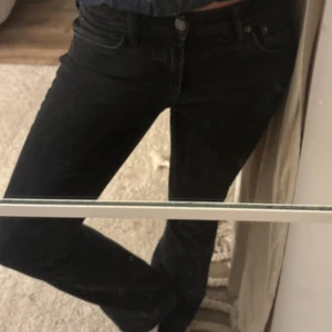 Svarta bootcut jeans - Svarta jeans med klassisk femficksdesign och bootcut ben. Sitter snyggt på höften och har en enkel knapp- och dragkedjestängning. Perfekta för dig som gillar en tidlös och clean look.