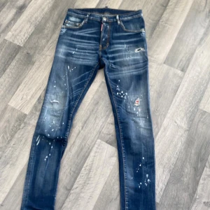 Dsquared2 skinny jeans med färgstänk - Snygga blå skinny jeans från Dsquared2 med coola färgstänk och slitningar på benen. Klassisk femficksmodell med låg midja och detaljerade sömmar. Jeansen har en modern, smal passform och är tillverkade i stretchig denim för extra komfort.