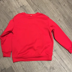 Röd sweatshirt i storlek S - En enkel och stilren röd sweatshirt i storlek S. Tröjan har rund hals, långa ärmar och ribbade muddar vid ärmslut och nederkant. Perfekt för dig som gillar en klassisk look med lite färg. Materialet känns mjukt och bekvämt mot huden.