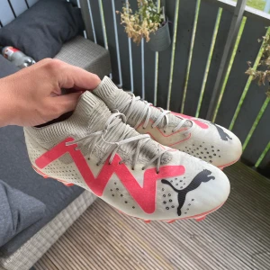 Puma Future - Säljer ett par snygga fotbollsskor från Puma i vitt med rosa detaljer och svarta Puma-loggor. De är fg/ag/ MG allstå gjorda för både konstgräs och vanligt gräs. Köptes in 2024 men säljs för de inte används särskilt ofta. Kan gå ner lite i pris✌️