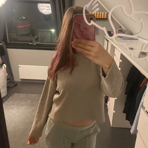 Beige stickad tröja med lång ärm - Mysig beige stickad tröja med lång ärm och ribbade muddar. Tröjan har en loose passform och är lite croppad, vilket gör den perfekt att styla med höga byxor. Enkel och stilren design utan mönster eller detaljer, passar dig som gillar neutrala färger.