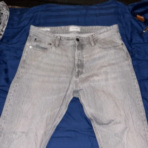 Gråa relaxed jeans från Jack & Jones - Säljer ett par ljusgrå jeans från Jack & Jones i modellen Relaxed/Chris. Strl 34/32 Jeansen har en avslappnad passform, klassisk femficksdesign och är tillverkade i bomull. Perfekta för en chill och stilren look.