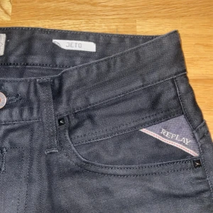 Svarta Replay Jeto jeans - Snygga svarta jeans från Replay, modell Jeto. Klassisk femficksdesign med Replay-logga på myntfickan och röd R-detalj på bakfickan. Jeansen har raka ben och är tillverkade i ett mjukt bomullstyg med stretch för extra komfort.