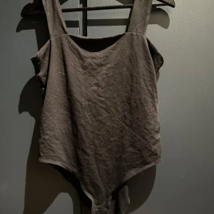 Svart body från H&M - En stilren svart body från H&M med breda axelband och klassisk skärning. Tillverkad i mjukt material som sitter skönt mot kroppen. 