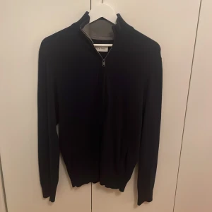 Mörkblå tröja med dragkedja - Mörkblå kofta från Pier One med hel dragkedja framtill och hög krage. Tröjan har en normal passform. Aldrig använd så i väldigt bra skick. Storlek S. Hör av er vid frågor!