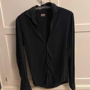 Mörkblå Sonrisa skjorta i bomull - Mörkblå skjorta från Sonrisa med klassisk krage och långa ärmar. Skjortan har knappar framtill och vid ärmsluten, vilket ger en clean och stilren look. Inköpt februari 2025 NK Göteborg. Nypris 2500 SEK.