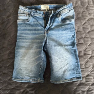 Blå jeansshorts från Produkt - Snygga blå jeansshorts från Produkt med klassisk femficksdesign och dragkedja. De har en rak passform och är tillverkade i slitstark bomull. Perfekta för varma dagar när du vill ha en avslappnad och cool stil.