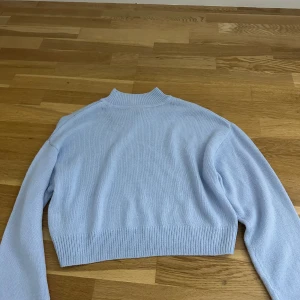 Ljusblå stickad tröja från H&M Divided - Supersöt ljusblå stickad tröja från H&M Divided i storlek XS. Tröjan har en croppad passform, ribbad kant nedtill och vid halsen samt långa ärmar. Perfekt för att ge din outfit en fräsch och chill vibe.